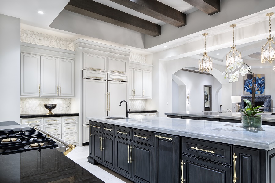 Modern kitchen with three gold, ornate pendant lights over the bar and wood beams on the ceiling. 